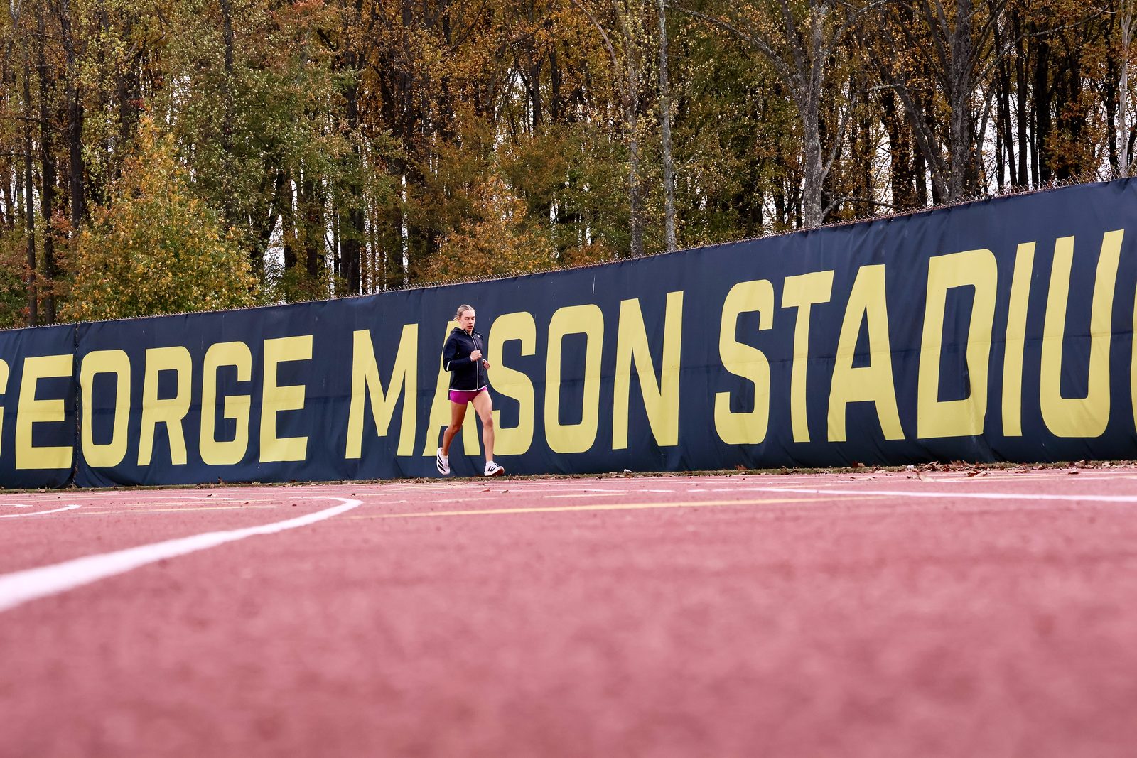 A solitary cross-country runner passes the home banner during workout. 