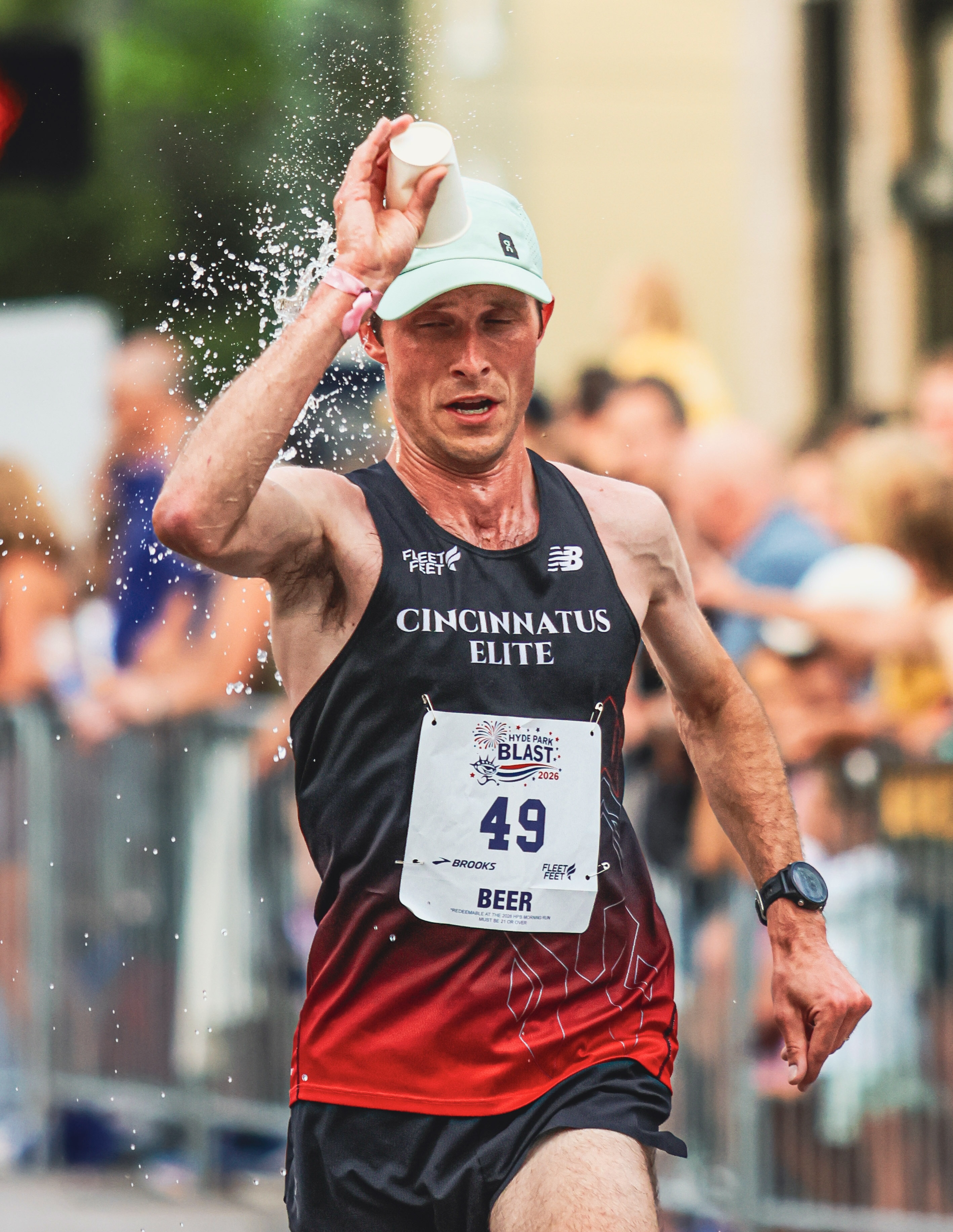 Runner dumps water over his head to cool off during a summer road race.