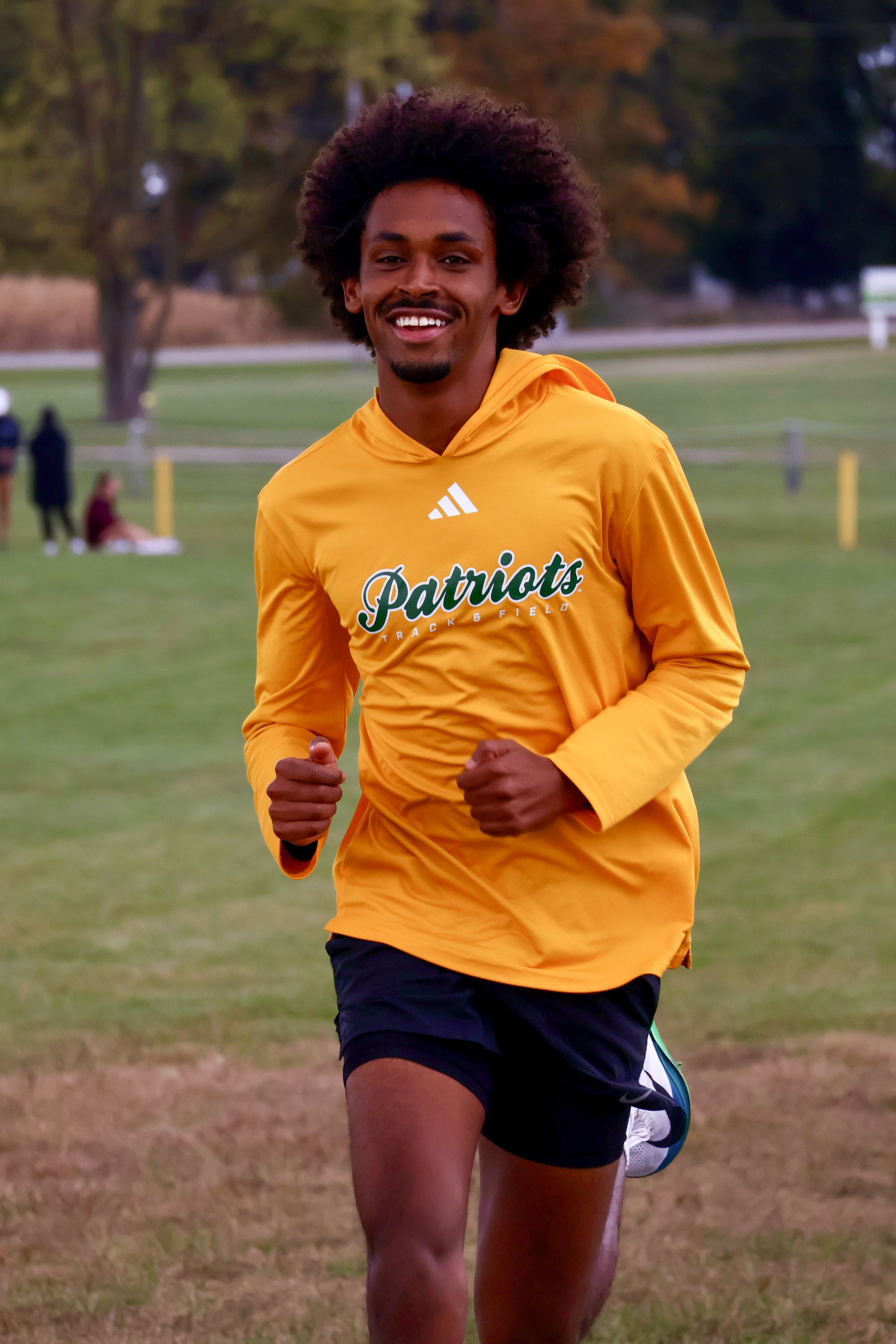 Runner smiles, mid-stride, in an open field.