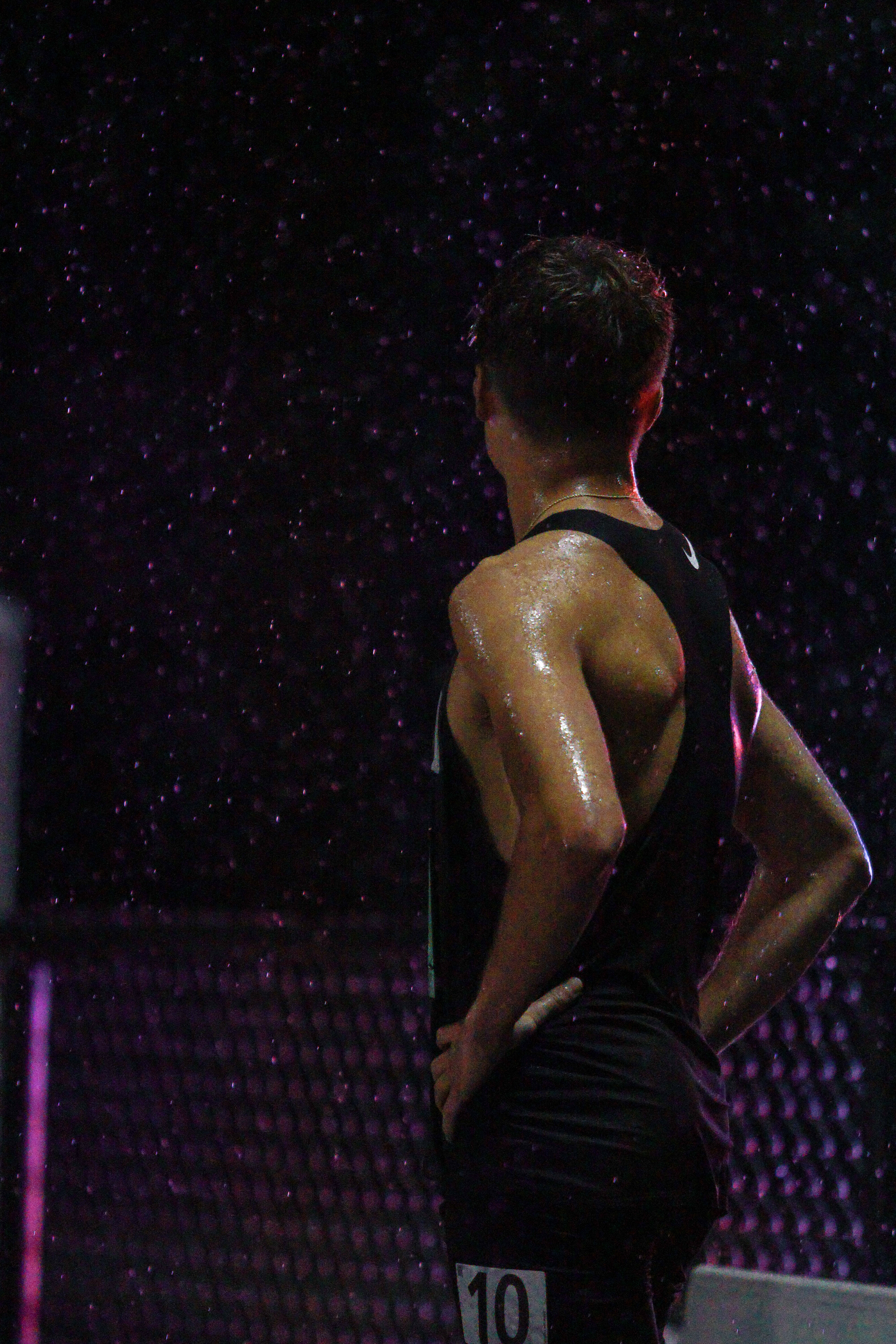 Runner prepares for race under rainy conditions with neon lights. 